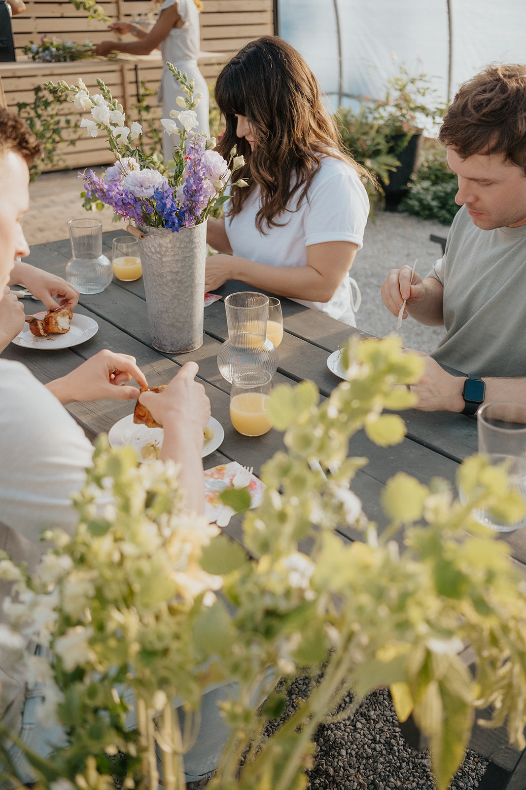 People sitting around a table outdoors with flowers and drinks